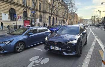 Varios coches circulan por una calle de París.