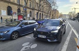 Varios coches circulan por una calle de París.