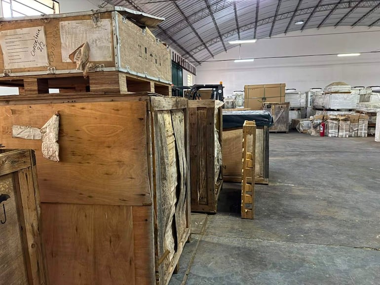 Cajas de madera apiladas en un almacén, algunas abiertas, reflejan deterioro de equipos médicos del IPS.