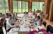 Antonio Carlos Barrios Fernández, Juan Carlos Baruja y Sergio Daniel Godoy Codas sonríen en un brunch elegante con mantel blanco.