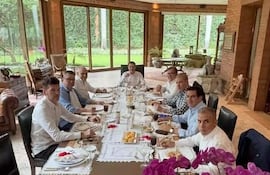 Antonio Carlos Barrios Fernández, Juan Carlos Baruja y Sergio Daniel Godoy Codas sonríen en un brunch elegante con mantel blanco.
