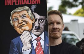 Un manifestante en Sudáfrica sostiene una pancarta con la imagen del presidente estadounidense Donald Trump y de Adolf Hitler frente a la Embajada de Estados Unidos durante una protesta bajo el lema "Manos Fuera de Venezuela".