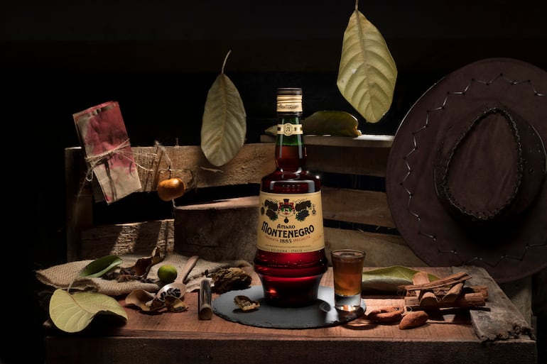 Botella de Amaro Montenegro y diversas especias tropicales como pimienta, café, cáscara de naranja, hojas. Licor legendario de Italia desde 1885.