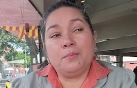 Clementina Ruiz Díaz Ojeda en chaqueta gris y blusa naranja, con expresión seria, sentada en un café, mirando hacia el exterior.