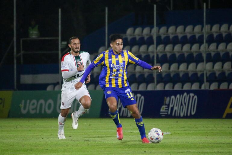 El mediocampista de Sportivo Luqueño, Víctor Sebastián Quintana maneja el esférico ante la persecución del volante de Atlético Tembetary, Willian Candia.