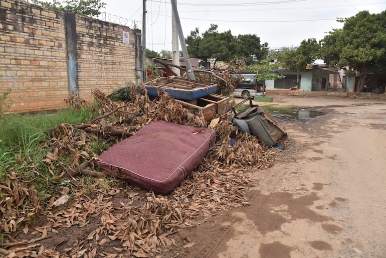 Montículo de residuos en calle de Bo San Pablo, incluyendo colchones y muebles, sin personas visibles.