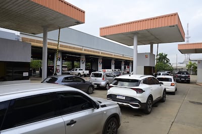 Área de espera con varios vehículos en fila, bajo un cielo nublado, sin personas presentes.