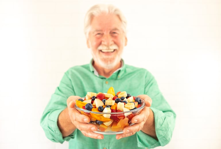 Hombre posa con un bowl de frutas.