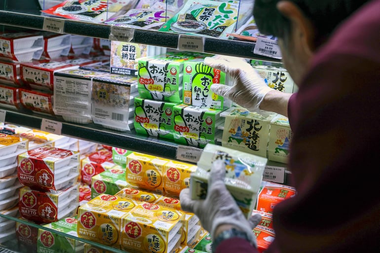 Esta fotografía, tomada el 8 de mayo de 2026, muestra a un trabajador reponiendo paquetes de natto, soja fermentada, en una tienda de comestibles japonesa del distrito de Manhattan, en la ciudad de Nueva York.