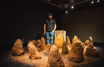 El artista Fidel Fernández posa con su instalación de takuru en el marco de la muestra "Cuadernos de campo", que fue adjudicada con el Premio AICA 2023.