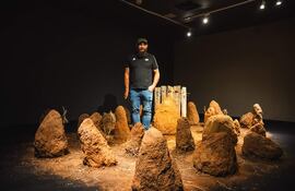 El artista Fidel Fernández posa con su instalación de takuru en el marco de la muestra "Cuadernos de campo", que fue adjudicada con el Premio AICA 2023.