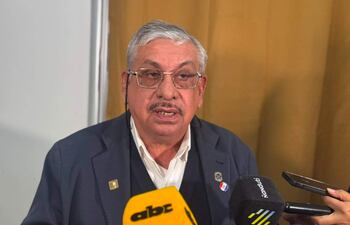 Isaías Ricardo Fretes en chaqueta oscura y camisa blanca, habla a varios micrófonos en sala de prensa.