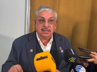 Isaías Ricardo Fretes en chaqueta oscura y camisa blanca, habla a varios micrófonos en sala de prensa.
