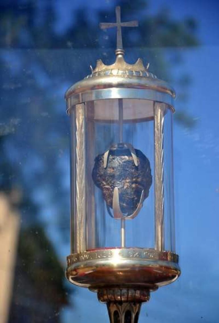 Reliquia del corazón de San Roque González en recipiente ornamentado, destacando en un entorno exterior con árboles y cielo despejado.