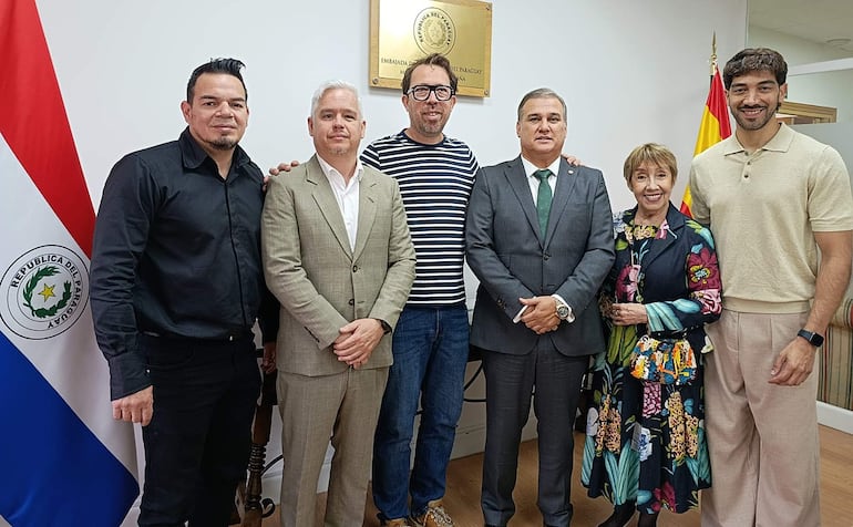 Martinessi en camiseta negra, Irún en vestido colorido, posan felices rodeados de amigos en la embajada.