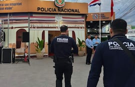 Dos policías en uniforme oscuro junto al edificio de la Policía Nacional, observando un entorno despejado y nublado.