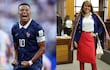 Mbappé en uniforme azul de Francia sonríe junto a mujer con blusa blanca y falda roja, en ambiente interior.