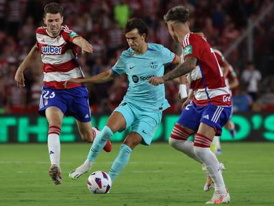 El delantero portugués del FC Barcelona João Félix (c) disputa un balón ante Ricard Sanchez  (d) defensa del Granada FC durante el encuentro correspondiente a la jornada nueve de primera división que disputan hoy Domingo frente al FC Barcelona en el estadio Nuevo Los Cármenes, en Granada.