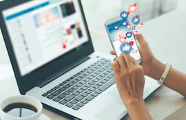Una mujer da likes en su teléfono a una publicación en Facebook.