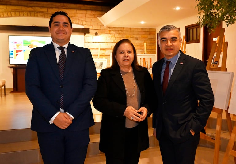 María Antonia Masana García sonríe en blusa clara y abrigo negro, junto a Jeison Granados en traje azul, posando con ambiente decorativo.