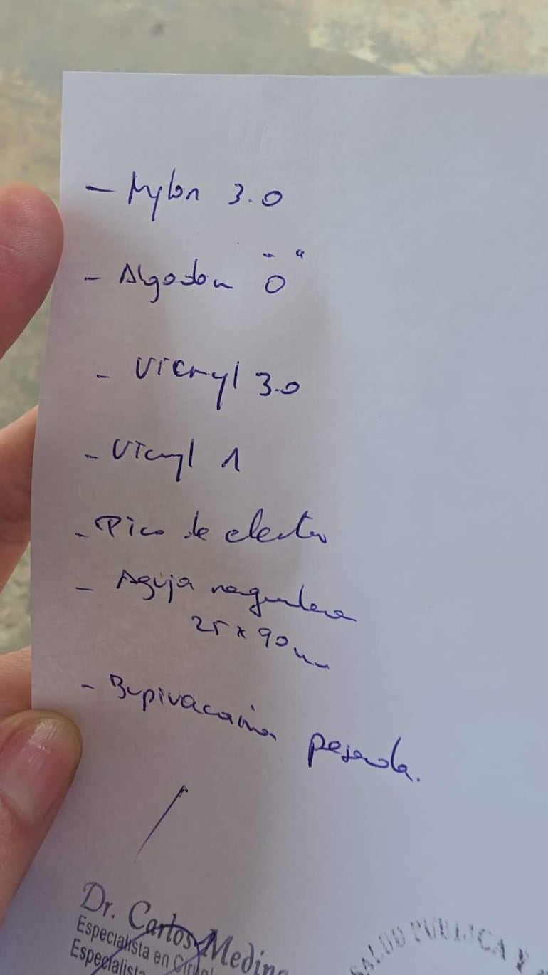 Mano sostiene receta con lista de materiales médicos, incluyendo nylon, algodón y bupivacaína pesada.
