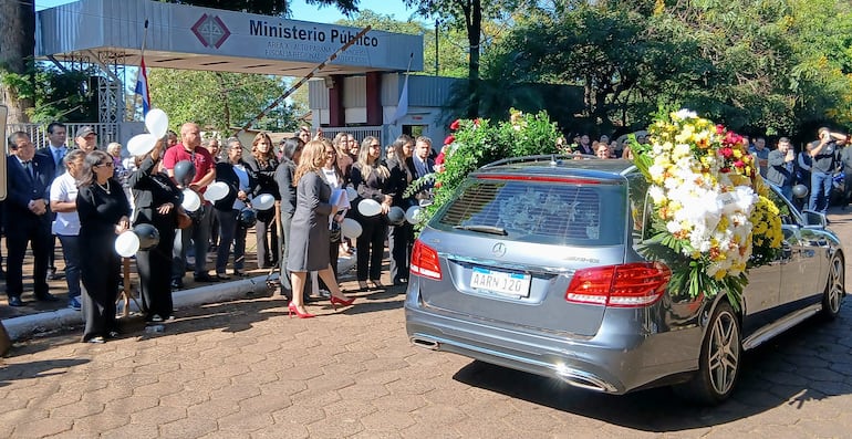 Ceremonia con personas en trajes oscuros y flores en un coche, en el Ministerio Público.