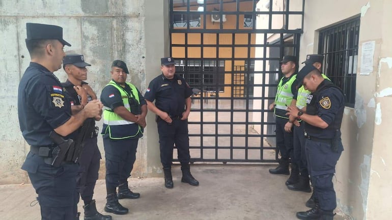 Siete policías, incluyendo un instructor activo, conversan en un entorno de seguridad frente a una reja metálica.