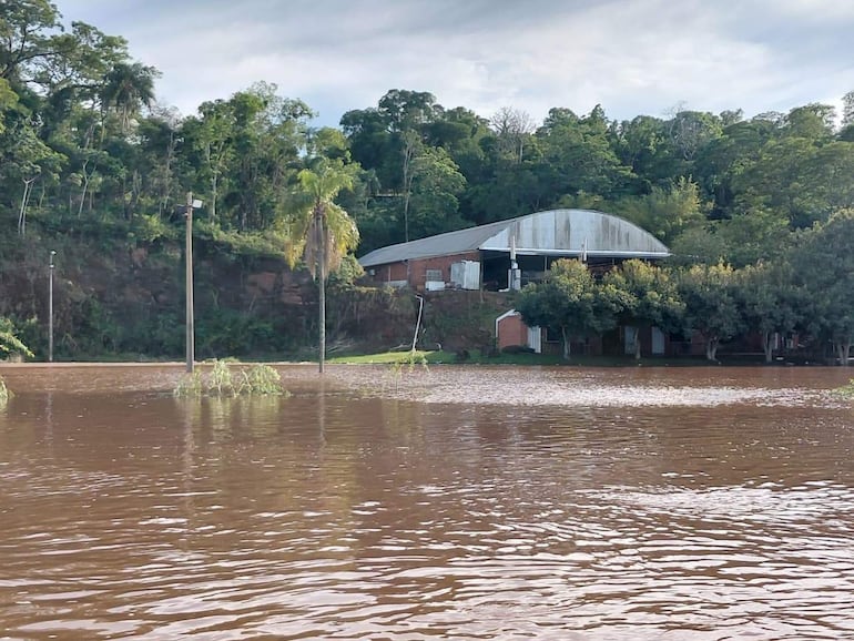 Estructura metálica y paredes de ladrillo rojo emergen de aguas inundadas en un paisaje desolado.