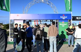Grupo de personas de pie en evento de Heineken, algunos ajustando cámaras y con indumentarias festivas en un ambiente alegre.