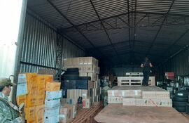 Los intervinientes revisan uno de los cinco depósitos encontrados dentro del predio allanado, en cuyo interior hallaron centenares de cajas con cigarrillos de distintas marcas  tabacaleras.