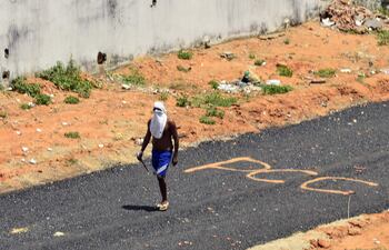 Fotografía de archivo. Un preso que camina armado sobre un tramo de vía en el que se leen las siglas del Primer Comando de la Capital (PCC).