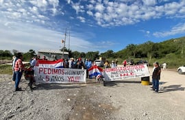 Veinte manifestantes sostienen carteles en colores de la bandera paraguaya, exigiendo un contrato y la destitución del presidente.
