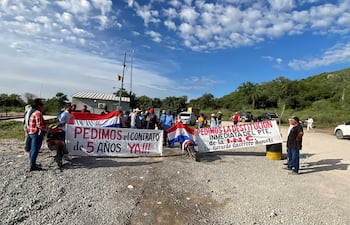 Veinte manifestantes sostienen carteles en colores de la bandera paraguaya, exigiendo un contrato y la destitución del presidente.