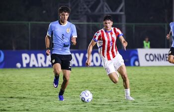 El delantero paraguayo Giovanni López (d) se escapa de la marca de un zaguero uruguayo.