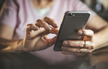Una adulta mayor realiza su fe de vida en el IPS en su teléfono celular.