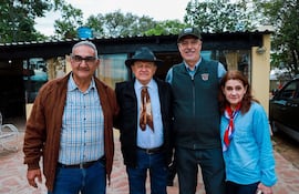 José Mutti y Arnoldo Wiens sonríen, mientras Arturo Martínez y Veronika Wiens posan con abrigo y chaleco en un jardín.