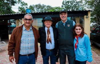 José Mutti y Arnoldo Wiens sonríen, mientras Arturo Martínez y Veronika Wiens posan con abrigo y chaleco en un jardín.