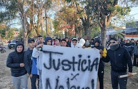 Jóvenes en sudaderas y chaquetas sosteniendo una pancarta que dice 'Justicia x Nahuel' con expresiones serias.
