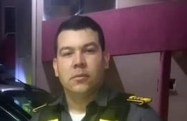Hombre en uniforme de seguridad de camisa gris y chaleco amarillo en un entorno urbano. Expresión neutral, posando para la cámara.
