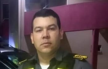 Hombre en uniforme de seguridad de camisa gris y chaleco amarillo en un entorno urbano. Expresión neutral, posando para la cámara.
