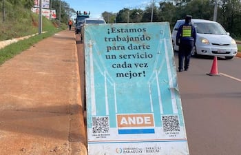 Agente de la Policía Municipal en chaleco reflectante dirige el tráfico junto a un cartel de la ANDE sobre trabajos en la calle.