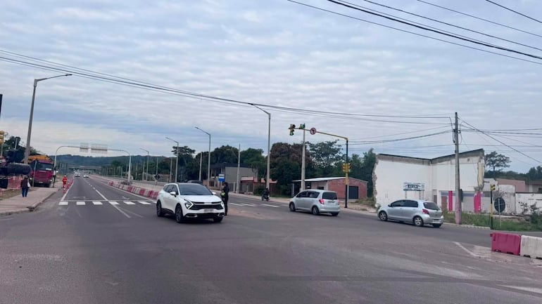 Tres vehículos en intersección de Ypacaraí, cielo nublado y semáforo visible; sin personas presentes.