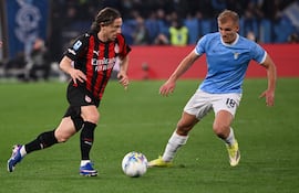 El centrocampista croata del AC Milan, Luka Modric (número 14), corre con el balón frente al delantero danés de la Lazio, Gustav Isaksen (número 18), durante el partido de la Serie A italiana entre la Lazio y el AC Milan en el Estadio Olímpico de Roma el 15 de marzo de 2026. (Foto de Alberto PIZZOLI / AFP)