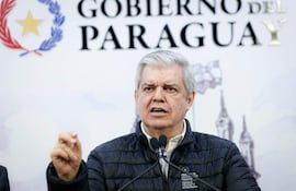 Hombre canoso en chaqueta negra, gesticulando con seriedad, en entorno oficial con fondo que dice 'GOBIERNO DEL PARAGUAY'.