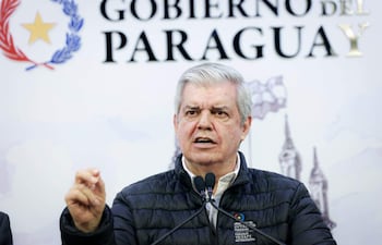 Hombre canoso en chaqueta negra, gesticulando con seriedad, en entorno oficial con fondo que dice 'GOBIERNO DEL PARAGUAY'.