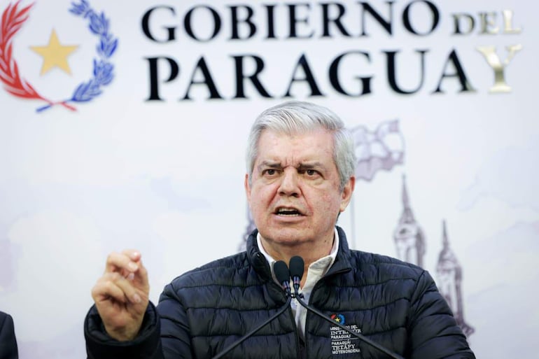 Hombre canoso en chaqueta negra, gesticulando con seriedad, en entorno oficial con fondo que dice 'GOBIERNO DEL PARAGUAY'.