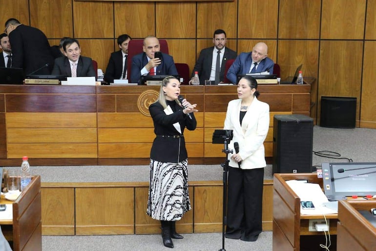 La senadora cartista Lizarella Valiente  canta con la artista Andrea Valobra vestida de blanco, mientras Bachi Núñez graba la escena.
