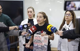 Rossana González con camiseta de 'SINA MED Paraguay' sostiene cartel de huelga, gesticulando mientras es observada por otras mujeres.