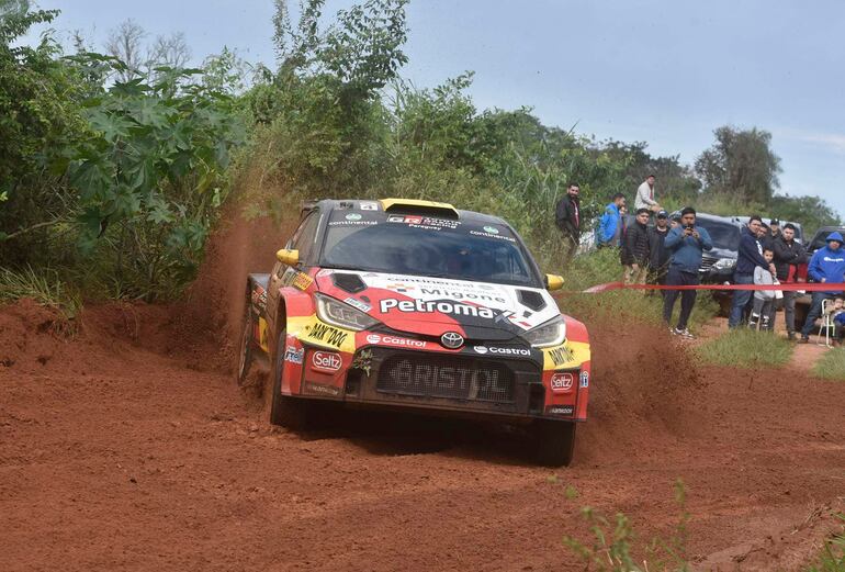 Toyota en acción, levantando polvo y barro, con espectadores entusiastas en el fondo, disfrutando de la competencia de rally.