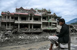 Un hombre descansa sentado frente a un edificio dañado por la riada en Nuwakot, Nepal.